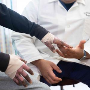 Image of Shriners Children's doctor examining a patient with burn injuries on his hand..