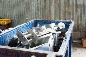 A large dumpster filled with various steel components and scrap metal, ready for recycling