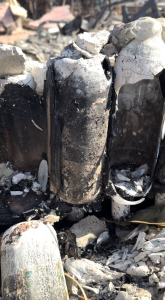 The remnants of white glass bottles, broken and charred are clustered together in the rubble of what used to be Jordan Catapano's home