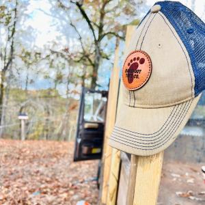 Picture of a hat hanging on a fence post with the words Barefoot Tree Company written on the hat.