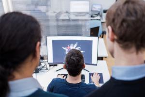 The Delta4 tech team at work at the computer using the proprietary platform Hyper-C