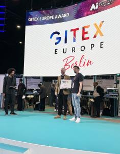 Two men stand on a stage as one presents the other with an award for a startup pitch competition.