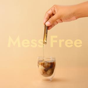 Hand squeezing a HUNY™ Shilajit Honey Stick into a cup of tea, demonstrating its convenience and ease of use.