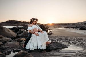 Maternity Couple enjoying a moment on the rocky beach, by Caryn Scanlan