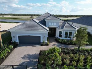 A newly constructed single-family home in the Esplanade at Starling community, featuring a modern gray tile roof installed by Gulf Western Roofing, a two-car garage, lush landscaping,and a scenic waterfront backdrop.