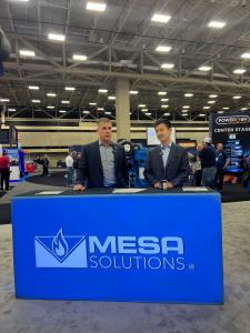 MESA Solutions CEO Scott Gromer and Modern Hydrogen CEO Tony Pan sign a partnership agreement at the POWERGEN International Conference in Dallas, TX, on February 11, 2025. They are standing behind a table with a blue MESA Solutions-branded tablecloth, eng