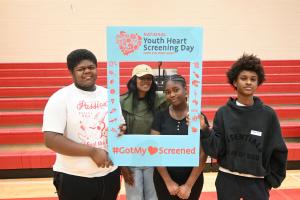 Four participants pose in a gym holding a #GotMy❤️Screened frame for National Youth Heart Screening Day, promoting early detection and prevention of sudden cardiac arrest in youth.