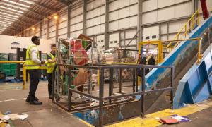 Warehouse staff with a roll cage of cardboard for recycling