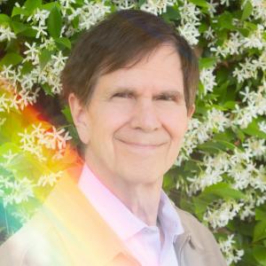 Brown haired gentleman in casual suit, standing outdoors with a splash of rainbow light