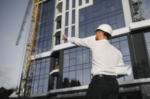 An architect at a commercial construction site points ahead, guiding as-built surveys to accurately document existing conditions.