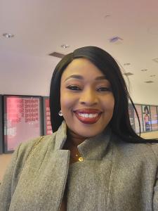 Esther Ijewere, a media strategist and founder of Women of Rubies, smiling warmly while wearing a stylish gray coat at an indoor event.