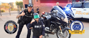 A young boy in a SWAT costume poses with a police officer next to a motorcycle, showcasing community engagement and support.