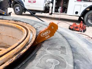 An OTR tire with one of AME's Gator Bites is shown as it is in place, helping a tire tech with the process of changing a large OTR tire.