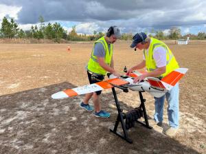 Two male students check an advanced unmanned fixed wing aircraft before flight as part of their UAS Bootcamp training from USI