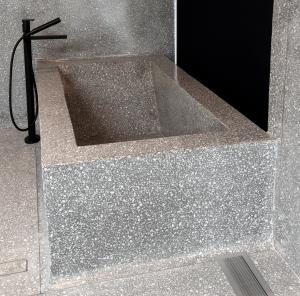 Terrazzo design: bathtub included in monochromatic cemetitious terrazzo installation in mid-century modern home design in Malibu.