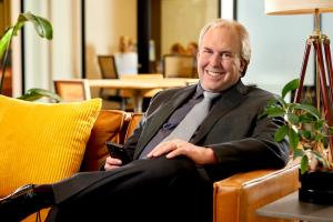 Paul Brennan, Managing Partner of Brennan Staffing Group, sitting on a couch—expert in Accounting, Finance, and HR staffing solutions.