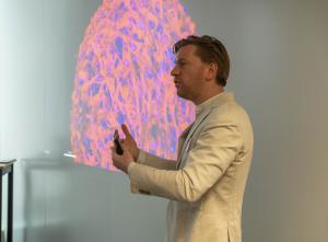 Meatable co-founder Daan Luining stands in front of a screen that shows a cell growing