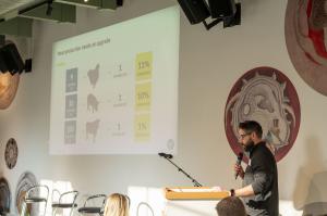 Alex Mayers stands in front of a screen that shows the current state of animal protein in the world.