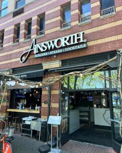 The Ainsworth Hoboken exterior with an open-air dining setup, featuring a bar, string lights, and brick facade. A prime destination for dining, cocktails, and events in Hoboken.