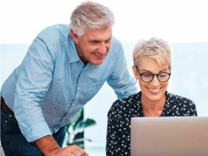 A retirement age couple is looking at the computer screen smiling.