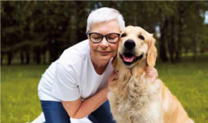 A retired lady is hugging a happy dog.