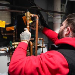 J. Blanton Plumbing technician working on a plumbing system, highlighting the company’s commitment to quality plumbing services, sewer line maintenance, and camera sewer inspections while sponsoring Chicago Tap Theatre's 2025 Gala.