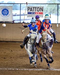 two people ride on horseback after a polo ball