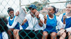 The photo shows a group of parents cheering at a sports event.
