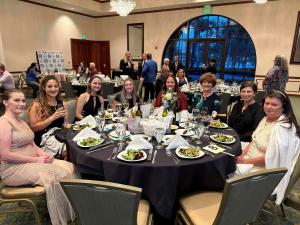A group of nine ladies sitting at an event table