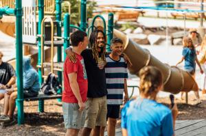 Three young adults stand side by side outdoors at camp.