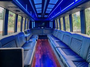 Interior view of a 30-passenger party bus by Skyline Party Buses in Tampa, with black diamond-stitched leather seating, LED ceiling lights, and wood flooring.