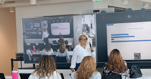 Dr. Vicki Wright Hamilton speaking into a microphone during a Cisco executive workshop, standing in front of a large screen showing a live poll question and responses from in-person and virtual attendees.