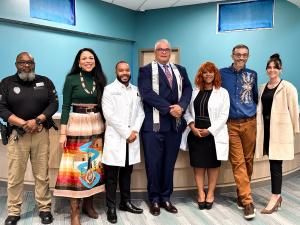 Nansemond Chief Keith Anderson, Assistant Chief Nikki Bass, and Fishing Point Board Chairman David Darling stand alongside medical staff at Fishing Point Healthcare, all smiling for a group photo inside the facility.
