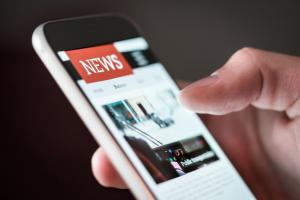 person scrolling through news on their phone