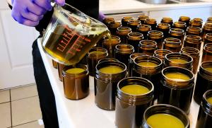 rows of jars of fresh salve poured with a gloved hand filling the last empty ones