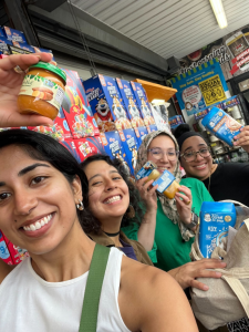 Four women smiling and holding up groceries purchased with WIC benefits, including Lulo co-founders Unnati Shuka and Dani Lopez, showing how Lulo works alongside families to understand real world WIC shopping challenges to build a platform that prioritize