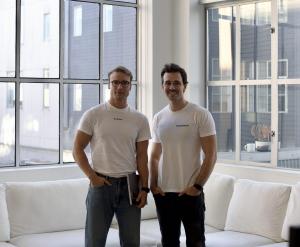 Die Gründer von beglaubigt.de, Felix Gerlach (l.) und Alexander Sporenberg (r.), stehen in einem modern eingerichteten Büro am Fenster und präsentieren ihr API-Produkt zur digitalen Unternehmensgründung.
