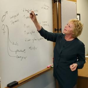 Dr E at a whiteboard in the lab, connecting notes about pH, good bacteria, and the shared microbiome.