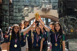 Girls cricket team celebrating their achievement, holding up their championship trophy at the Cricket awards event 2024