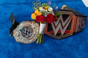 Two WWE Championship belts surround a wedding bouquet in blues, reds and yellows at Viva Las Vegas Weddings