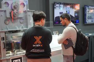 A visitor observes INTERX’s live press process demonstration at the booth.