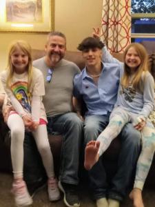 Jonathan Boyd sitting with his daughters and son on a couch, reunited as a family.