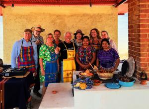 Group photo of international travelers smiling with Maya hosts after a community-led cooking experience in Antigua, Guatemala.
