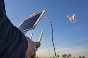 Drone flying in the sky and the operator looking at a screen