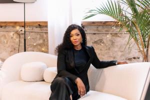 Kesiena “Sena” Edafiogho seated in a professional setting, smiling confidently. She is a tech entrepreneur and founder of Synergy One Consulting, known for empowering immigrants in Canada’s tech industry