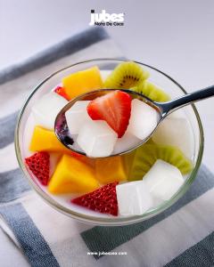 Bowl of fresh fruit topped with chewy Jubes coconut gel cubes, creating a colorful and refreshing tropical dessert.