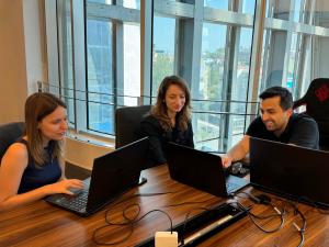 Three Tor.app team members working together at laptops in a modern office, developing AI productivity tools for transcription, content writing, and text-to-speech solutions.