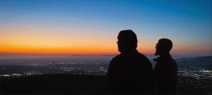 blue and gold sunset over the pacific with artists in silhouette