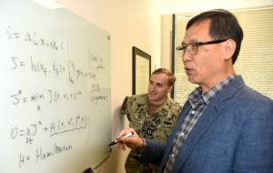 U.S. Navy Lt. Michael “Tom” Piscopo, an NPS student pursuing a dual master’s degree in mechanical engineering and applied mathematics, discusses dynamic systems equations with NPS Professor of Applied Mathematics Wei Kang.