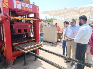 The image is of the Good Bricks machine where a set of bricks has just been produced and coming out from the machine, with no use of coal or firing and a much more environmentally friendly approach.